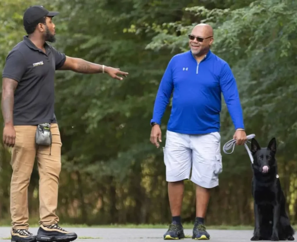 Kenneth Merritt from Merritt Dog Training doing a one on one private lesson with a German shepherd and its two owners. They are walking down a road in a park in Charlotte North Carolina.