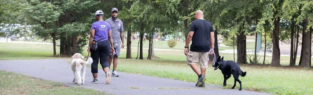 Kenneth-Merritt-from-Merritt-Dog-Training-walking-with-a-dog-and-its-owners-in-a-dog-park